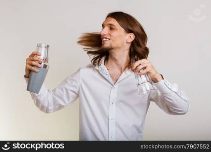 Young stylish man bartender with shaker making alcohol cocktail drink studio shot on gray