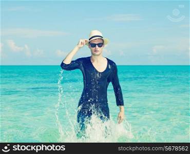 Young stylish man in the hat jumps on the sea