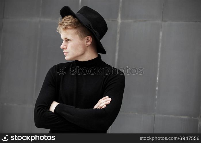 Young stylish man in trendy wear is looking away while standing outdoors. Street style.. Young stylish man in trendy wear is looking away while standing outdoors. Street style