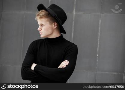 Young stylish man in trendy wear is looking away while standing outdoors. Street style.. Young stylish man in trendy wear is looking away while standing outdoors. Street style