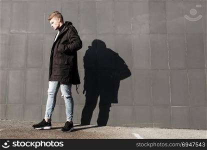 Young stylish redhead man in trendy outfit posing against urban background. Young stylish redhead man in trendy outfit posing against urban background.