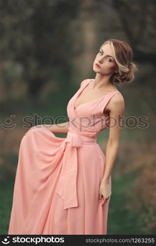 young stylish woman outdoors in the spring park. blonde girl with hairstyle in pink dress possing. selective focus.. young stylish woman outdoors in the spring park. blonde girl with hairstyle in pink dress possing. selective focus