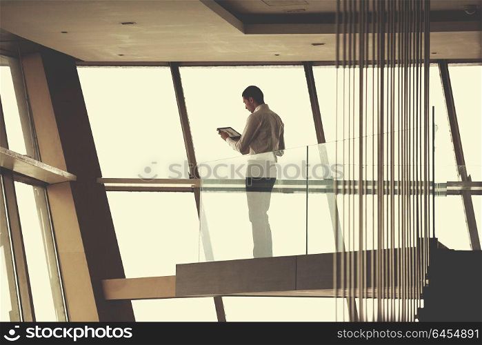 young successful business man in penthouse working on tbalet, modern bright duplex office apartment interior with staircase and big windows