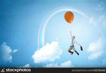 Young successful businessman flies on colorful balloon. Man flying in sky
