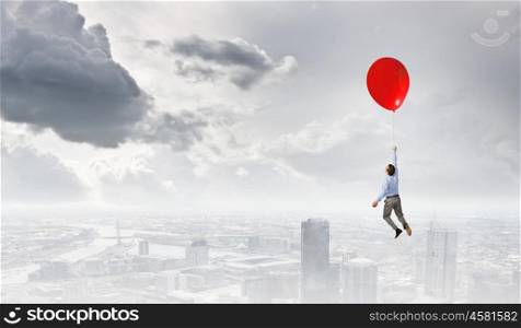 Young successful businessman flies on colorful balloon. Man flying in sky