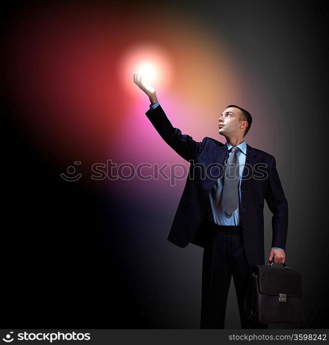 Young successful businessman holding a shining light in his hand as a symbol of success and advancement.