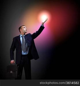 Young successful businessman holding a shining light in his hand as a symbol of success and advancement.