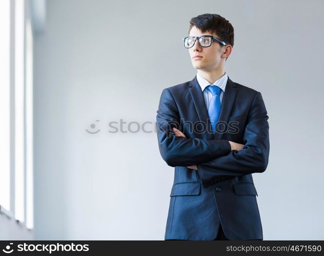 Young successful businessman. Image of handsome businessman in glasses with arms crossed on chest