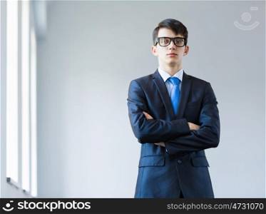 Young successful businessman. Image of handsome businessman in glasses with arms crossed on chest