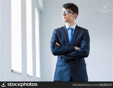 Young successful businessman. Image of handsome businessman in glasses with arms crossed on chest