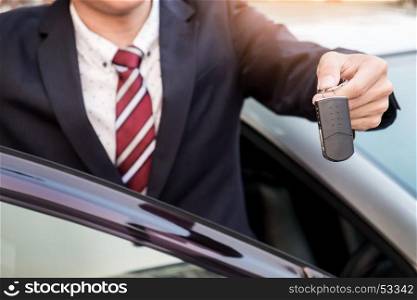 Young successful businessman offering a car key. Close-up of driver's hand showing key.