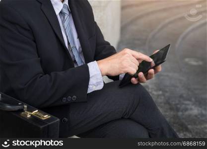 Young successful businessman using tablet for working in park outdoors.