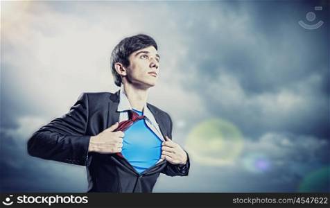 Young superhero businessman. Image of young businessman showing superhero suit underneath his shirt