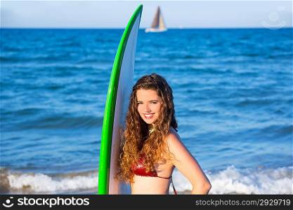 Young surfer girl holding surfboard in blue beach