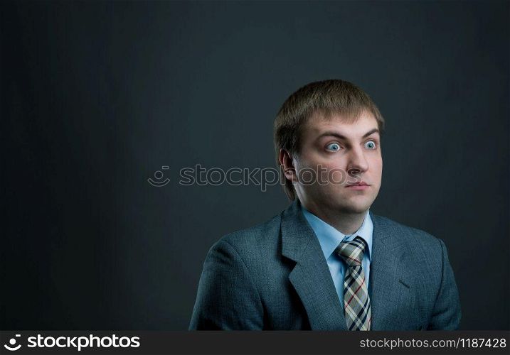 Young surprised businessman in suit and tie on black background. Thoughtful businessperson, male manager shocked. Young pensive businessman on black background