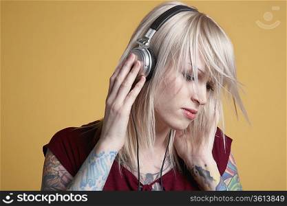 Young tattooed woman listening to music on headphones