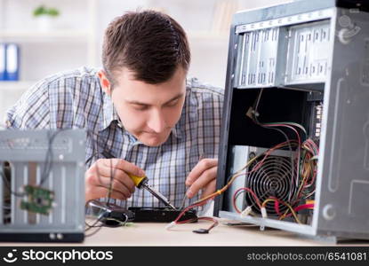 Young technician repairing computer in workshop