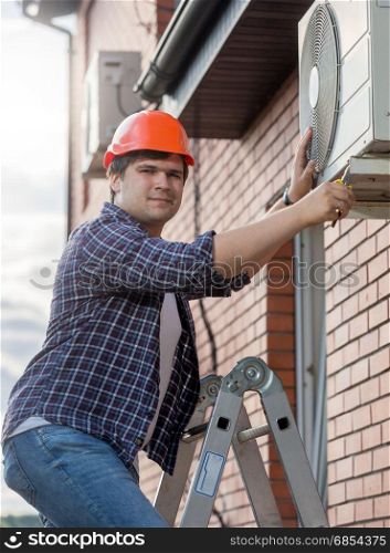 Young technician repairing outside air conditioning unit