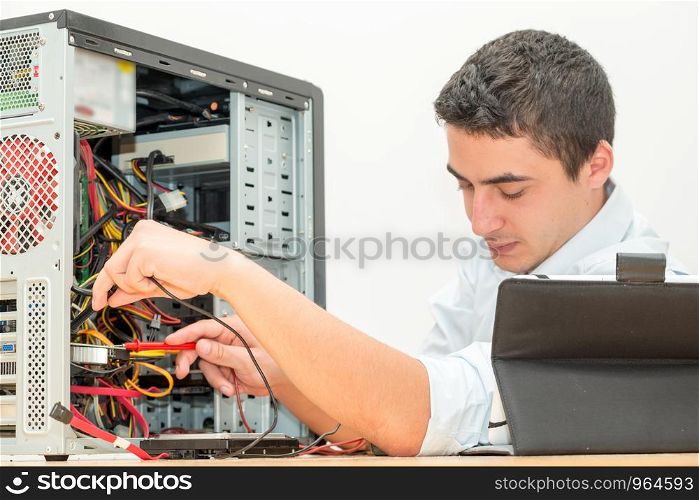 young technician working on broken computer in his office