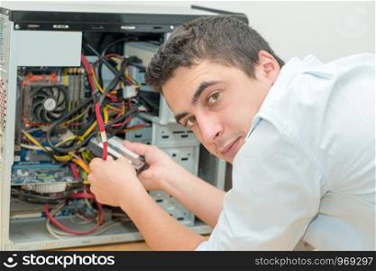 young technician working on broken computer in his office
