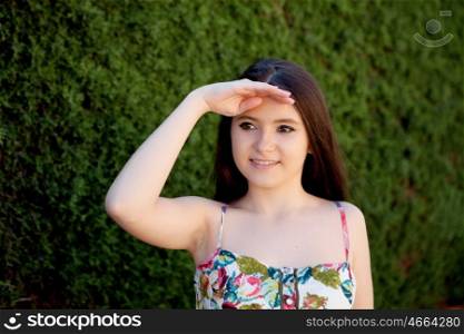 Young teen looking something outdoor with a natural green background