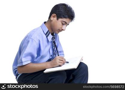 Young teenage boy drawing in book against white background