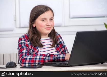 young teenage girl doing her homework with laptop