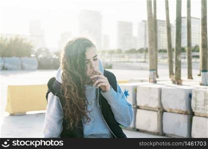 Young teenage girl sits down while she smokes