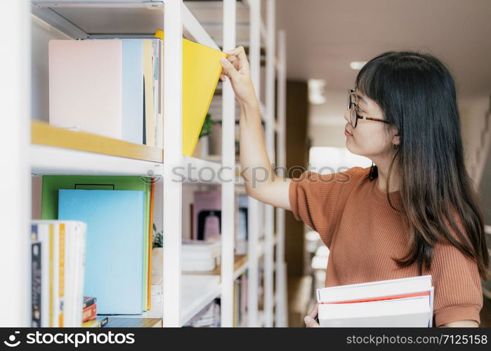 Young teenage making order on bookshelves. Student picking literature for education checking information in books store. Education concept.