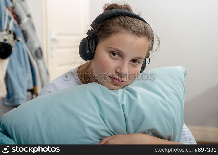 young teenage sitting on a bed in bedroom listen to music with headphones