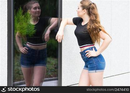 Young teenage woman wearing denim shorts and black crop top. Female presenting fashionable summer outfit.. Fashionable teen presenting summer outfit