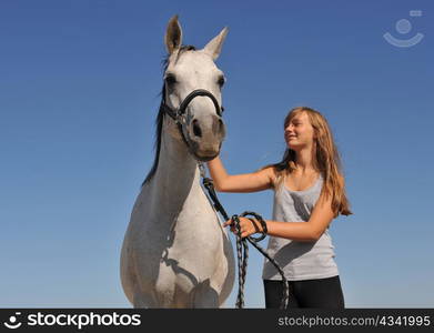 young teenager and her gray arabian horse on a blue sky