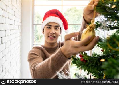 Young Teenager asian man decorating Christmas tree prepare for Christmas party holiday with his girlfriend