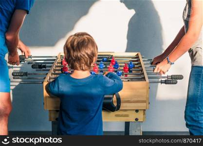 Young teenager boy playing table football with another player. Young people having fun, spending time together