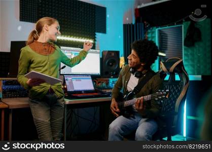 Young teenager girl singing song track with man guitarist record new single in recording studio. Young girl singing song mixing track with man guitarist