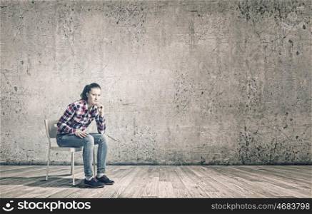 Young teenager girl. Young woman sitting on chair in empty room