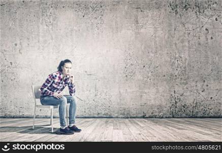 Young teenager girl. Young woman sitting on chair in empty room