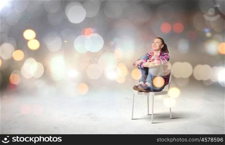 Young teenager girl. Young woman sitting on chair with bokeh lights at background