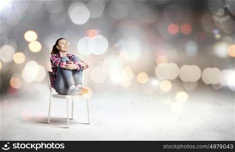 Young teenager girl. Young woman sitting on chair with bokeh lights at background