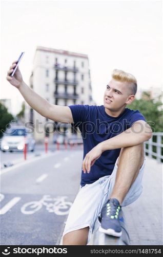 Young teenager sitting outdoors while taking a selfie