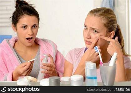 Young teenager with acne problem in the bathroom with friend