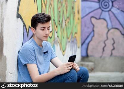 Young teenager with her cell phone and a wall of background painted with graffiti