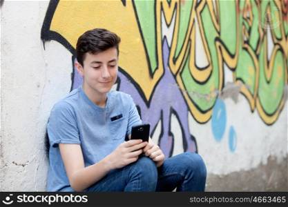 Young teenager with her cell phone and a wall of background painted with graffiti