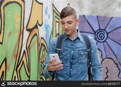 Young teenager with her cell phone and near of a wall painted with graffiti