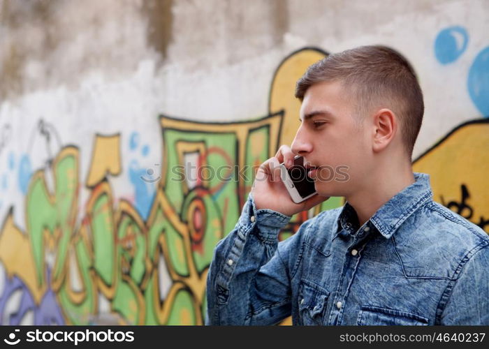 Young teenager with her cell phone and near of a wall painted with graffiti