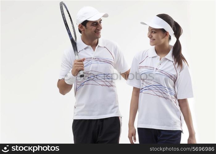 Young tennis players looking at each other against white background