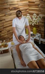 Young therapist massaging cleavage to attractive woman at spa