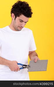 young tiler at work against yellow studio background