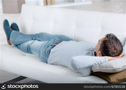 young tired man lying on sofa after cleaning