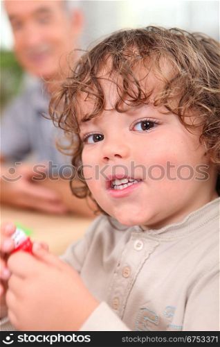 Young toddler with his grandfather in the background